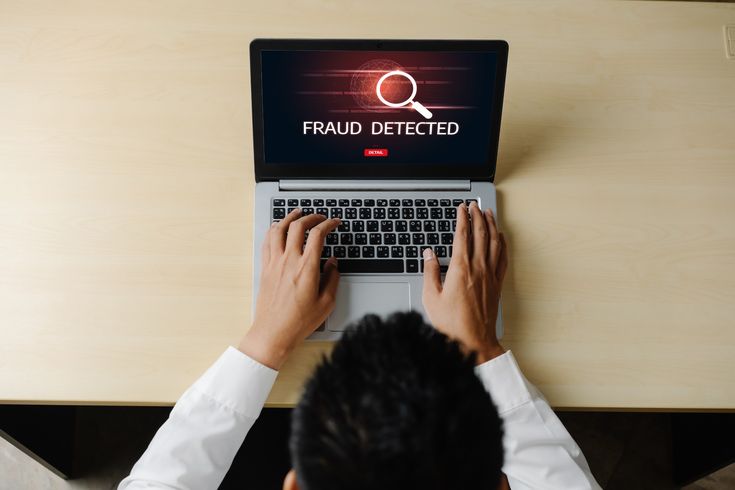 a picture of a man using a computer with a fraud alert